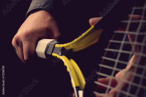 Hand on grip and swinging a tennis racket. Isolated on black bac