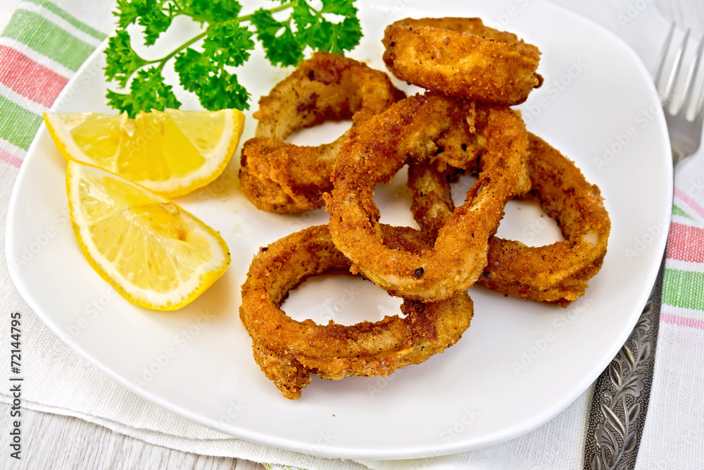 Calamari fried with lemon and fork on plate Calamari fried with lemon and fork on plate