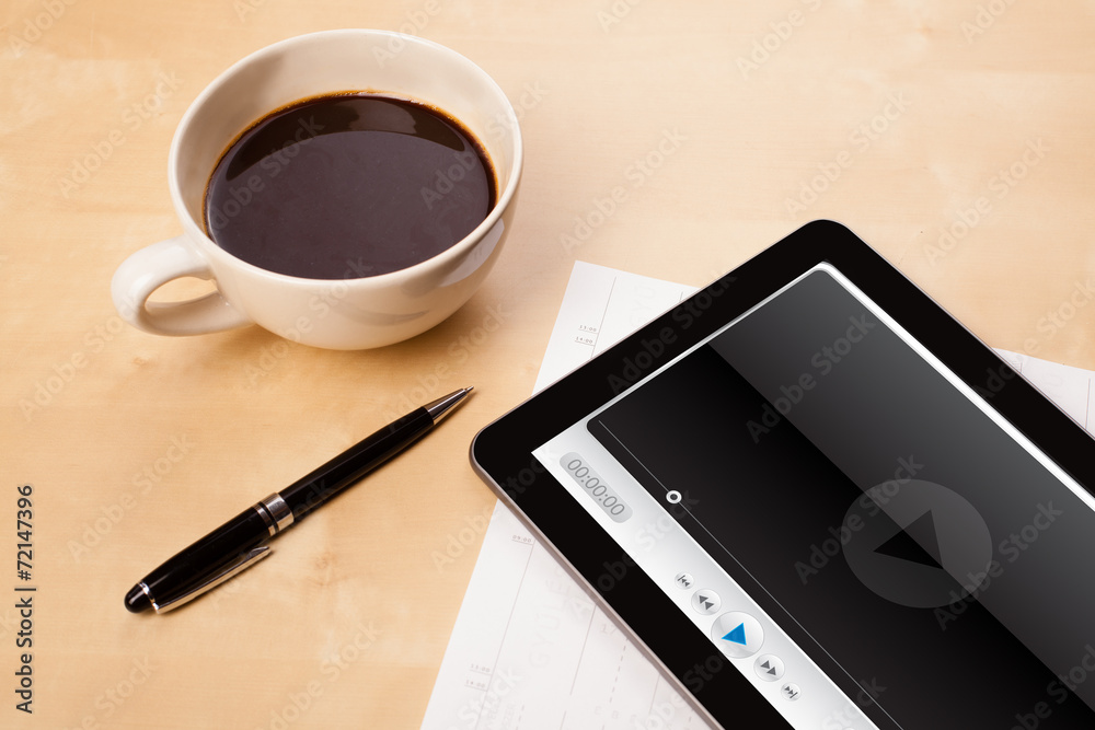 Tablet pc showing media player on screen with a cup of coffee on Tablet pc showing media player on screen with a cup of coffee on