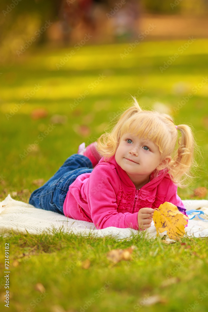Adorable little girl outdoors. lie on the grass. Autumn Park Adorable little girl outdoors. lie on the grass. Autumn Park