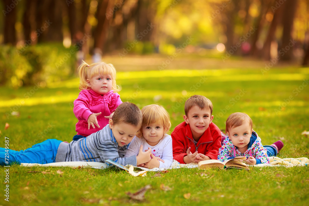 children in nature. reading a book outdoors lying on the grass children in nature. reading a book outdoors lying on the grass