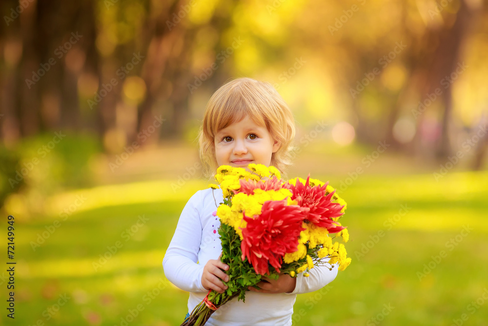 Adorable girl in the park with a bouquet of autumn flowers