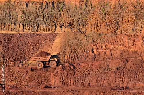 Loaded tip-truck going up along the open mine wall