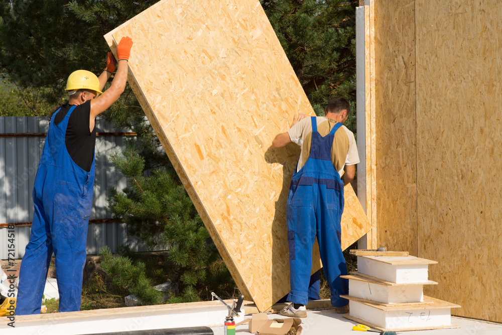Construction workers positioning wall panels