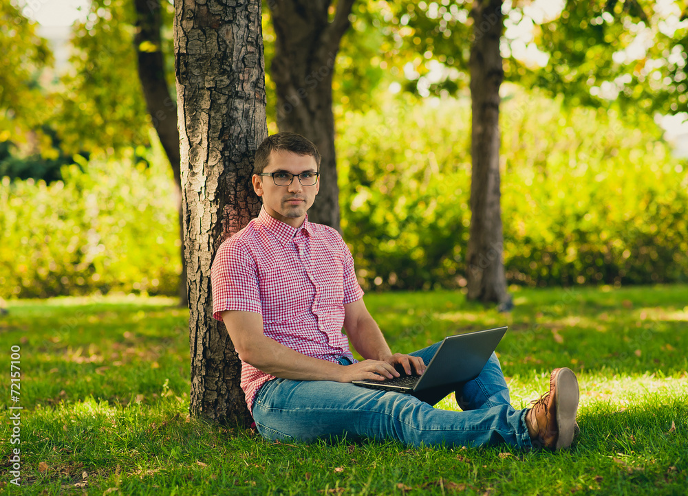 Young man sitting with Laptop Computer in the park