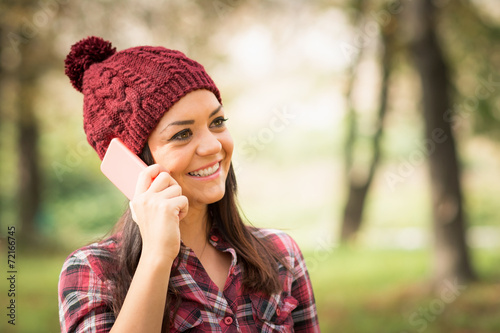 Young woman with beanie hat talking on the phone. No retouch.