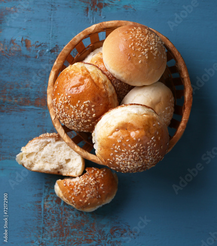 Tasty buns with sesame in wicker basket,