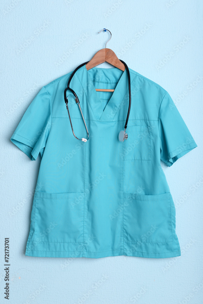 Doctor shirt with stethoscope on hanger on blue background Doctor shirt with stethoscope on hanger on blue background