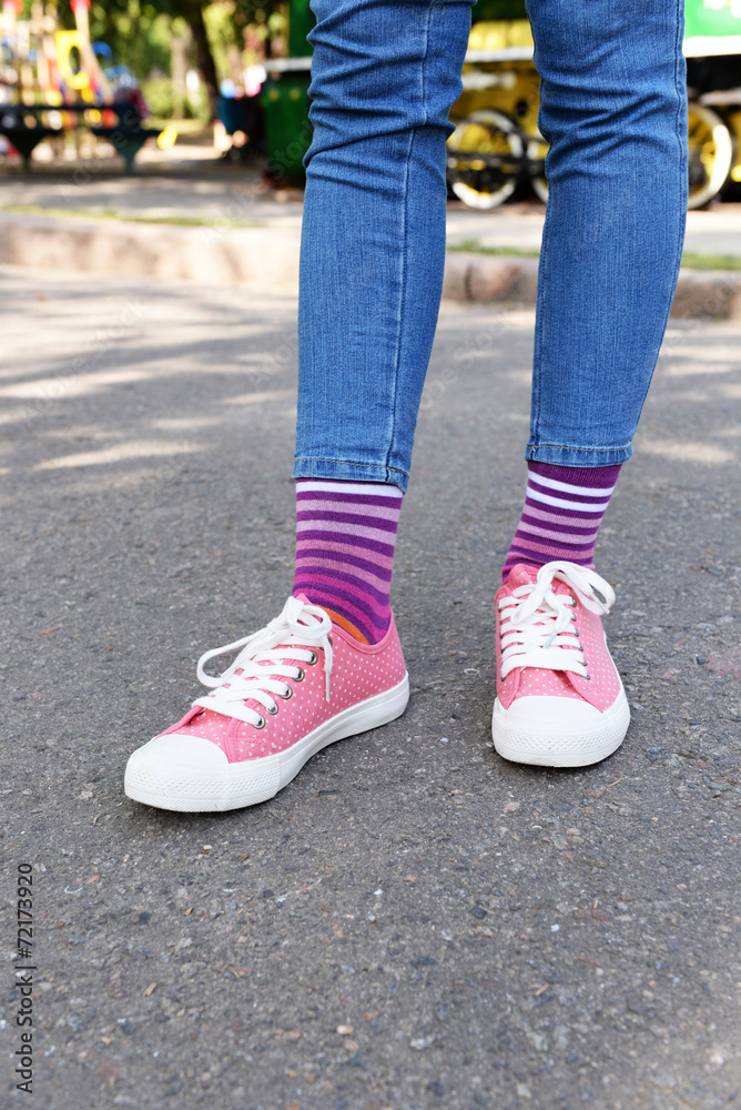 Female legs in colorful socks and sneakers outdoors