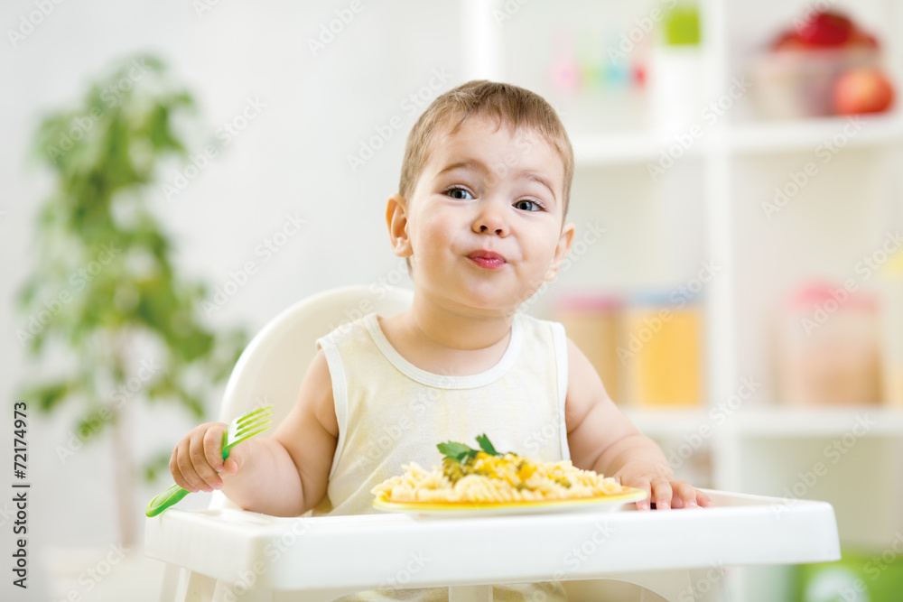 toddler boy in a highchair for feeding with a fork and a plate i toddler boy in a highchair for feeding with a fork and a plate i