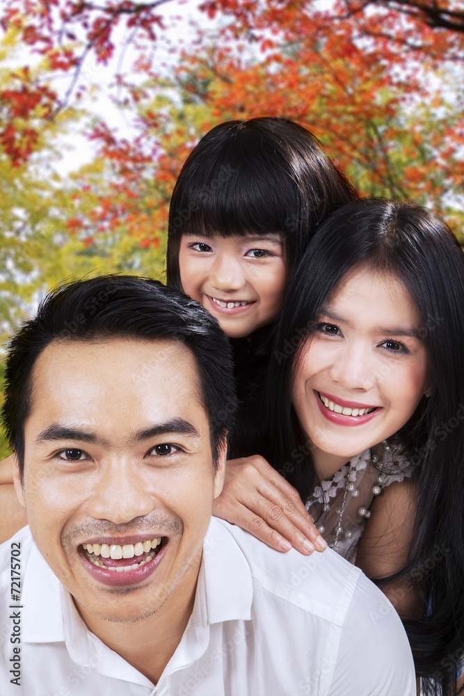 Fototapeta premium Attractive family smiling under autumn tree