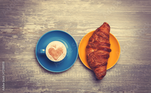 french croissant and cup of coffee on a wooden table