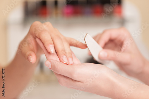 Fototapeta Woman in nail salon receiving manicure.