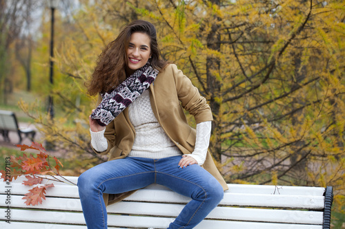 Beautiful woman sitting on a bench in autumn park