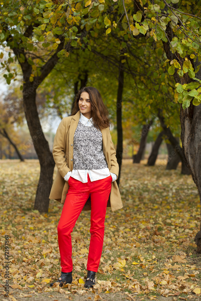 Young woman in fashion coat walking in autumn park Young woman in fashion coat walking in autumn park