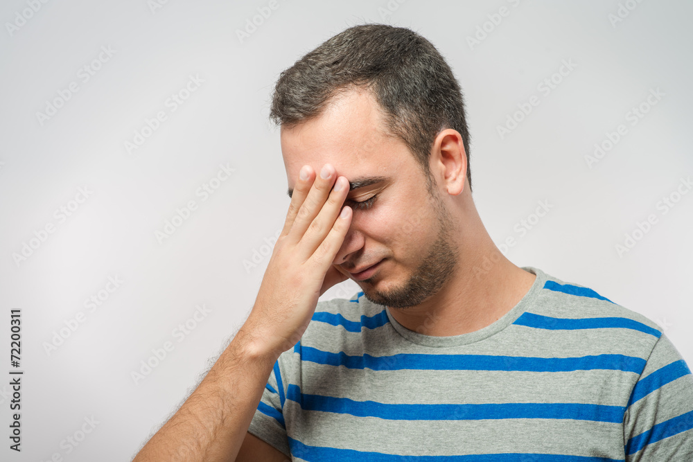 Desperate young man covering with his head in his hands Desperate young man covering with his head in his hands