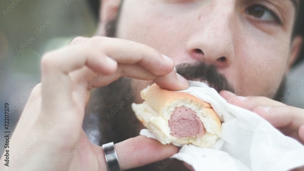young hipster man eating hotdog in the city young hipster man eating hotdog in the city