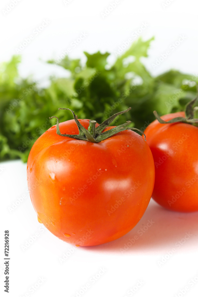 Red organic tomatoes in front of green lettuce