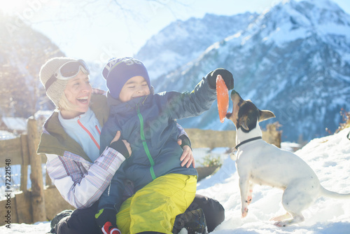 Happy family playing with a dog in a sun in Austrian Alps
