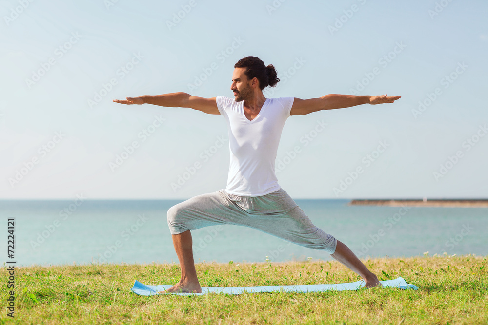 Fototapeta premium smiling man making yoga exercises outdoors