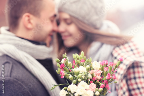 Billede på lærred Flowers and kissing couple in the background