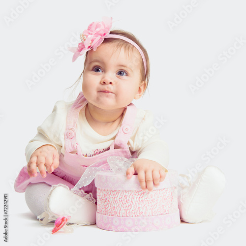 baby girl sitting on the floor with gift box  and looking up © tananddda