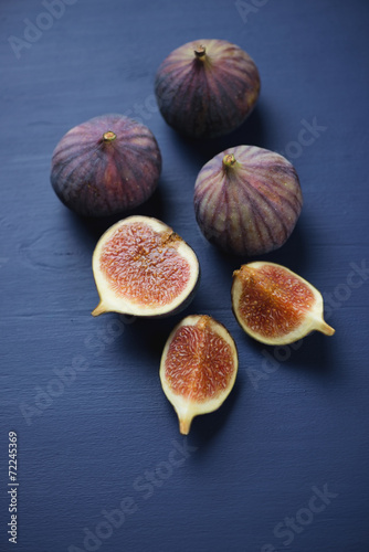 Close-up of ripe figs on a dark blue wooden surface, studio shot