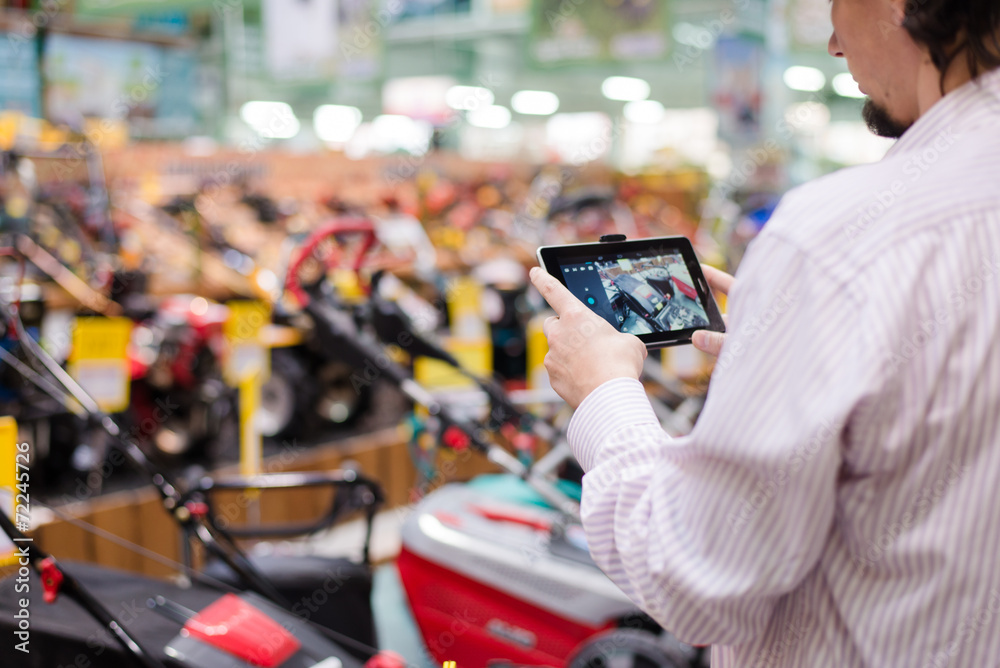 Man choosing lawnmowers in supermarket or DIY Man choosing lawnmowers in supermarket or DIY