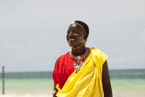 Young massai warrior man posing on bright sunny beach in Kenya photo