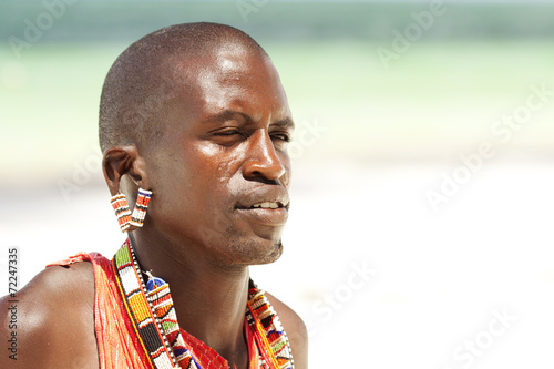 Young massai warrior man posing on bright sunny beach in Kenya