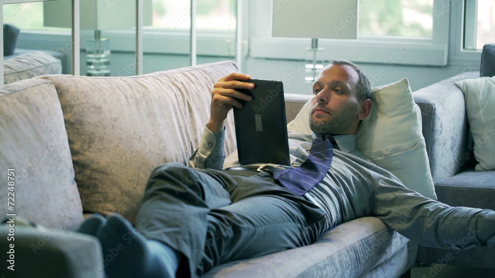 Businessman watching something on tablet and drinking juice Businessman watching something on tablet and drinking juice