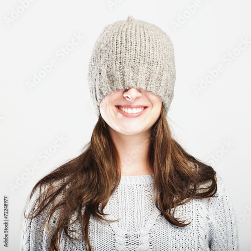 playful cute winter girl covers eyes with hat