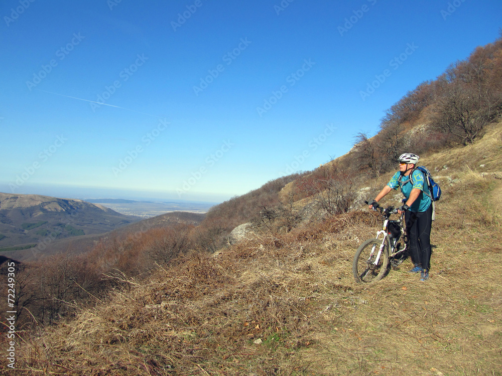 Young athlete standing on a rock with bicycle Young athlete standing on a rock with bicycle