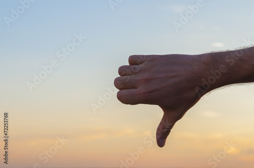 Hand at sunset sky background. KO sign
