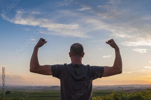 Man posing at sunset, sowing biceps. Nature background photo