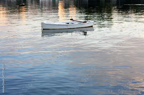 Small wooden boat during sunset. © jelena990