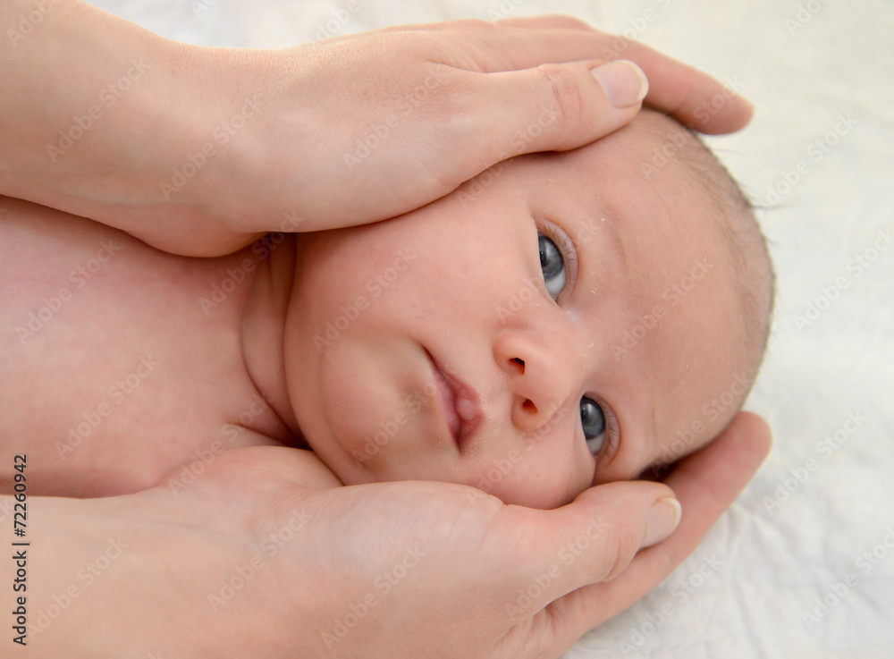 Mother's hands embrace the head of the baby Mother's hands embrace the head of the baby