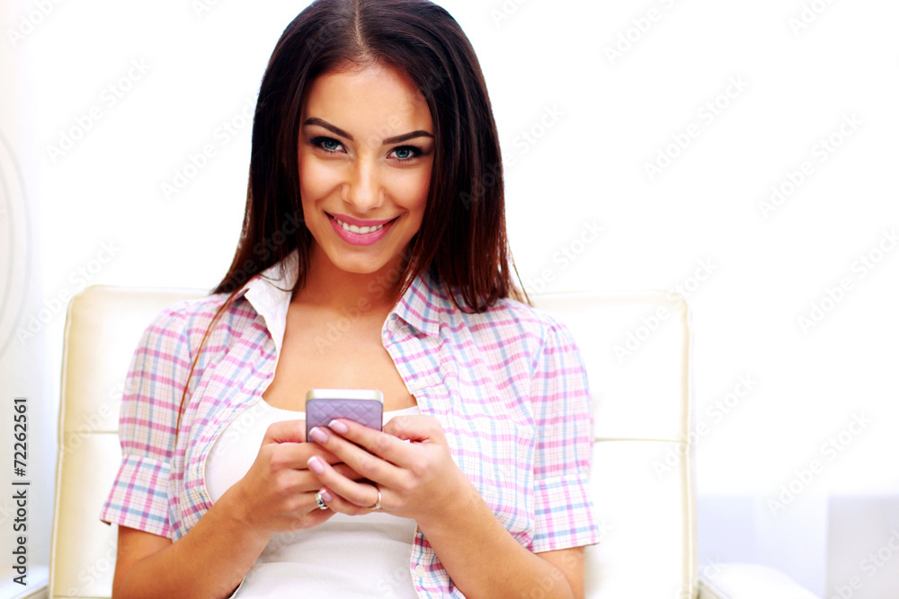 Smiling woman sitting on the sofa with smartphone Smiling woman sitting on the sofa with smartphone