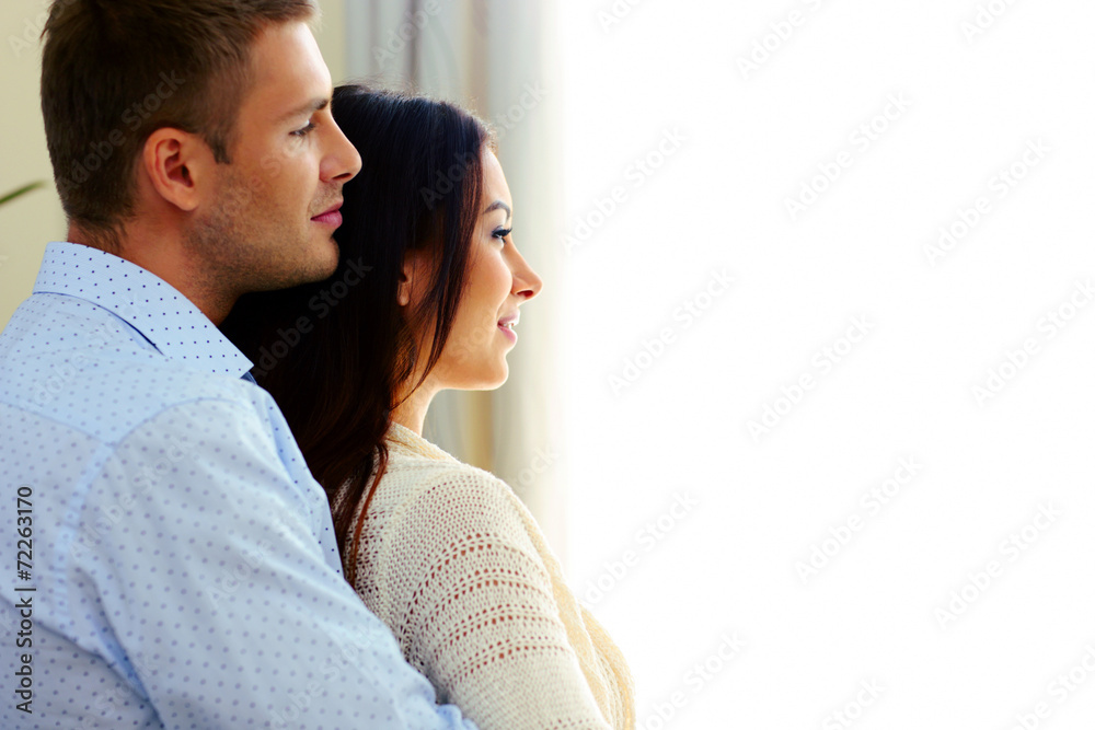 Side view portrait of a couple looking at window Side view portrait of a couple looking at window