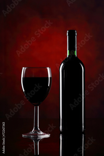 Red wine glass with bottle on the red background