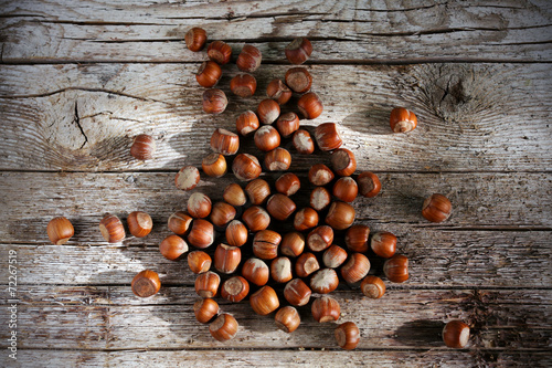 Bunch of hazelnuts scattered on a wooden table, autumn sunlight