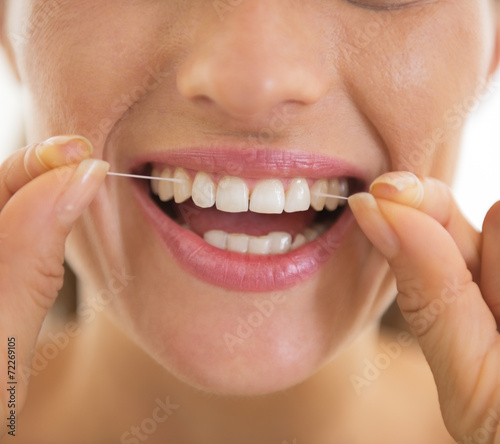 Closeup on young woman using dental floss