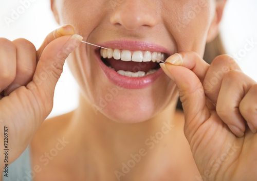 Closeup on young woman using dental floss