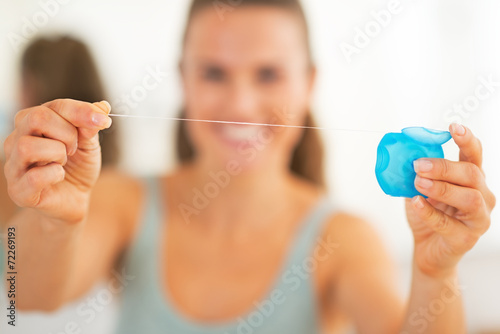 Closeup on happy young woman showing dental floss photo