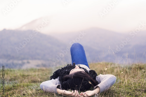 Young woman lying on the grass with Mountain view photo