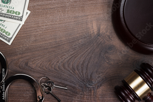 handcuffs gavel and money on wooden background