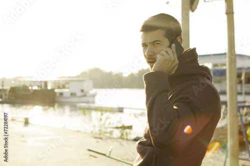 Handsome Man Talking On Mobile Phone At River Bank