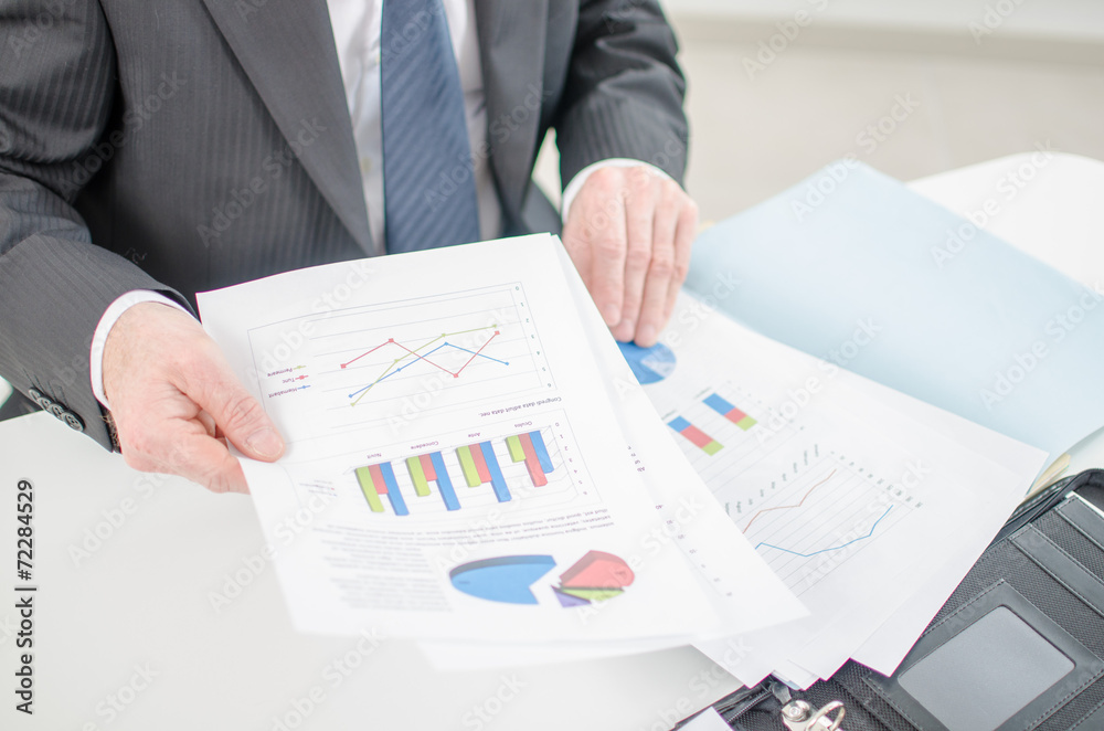 Businessman checking a file with financial graphs Businessman checking a file with financial graphs
