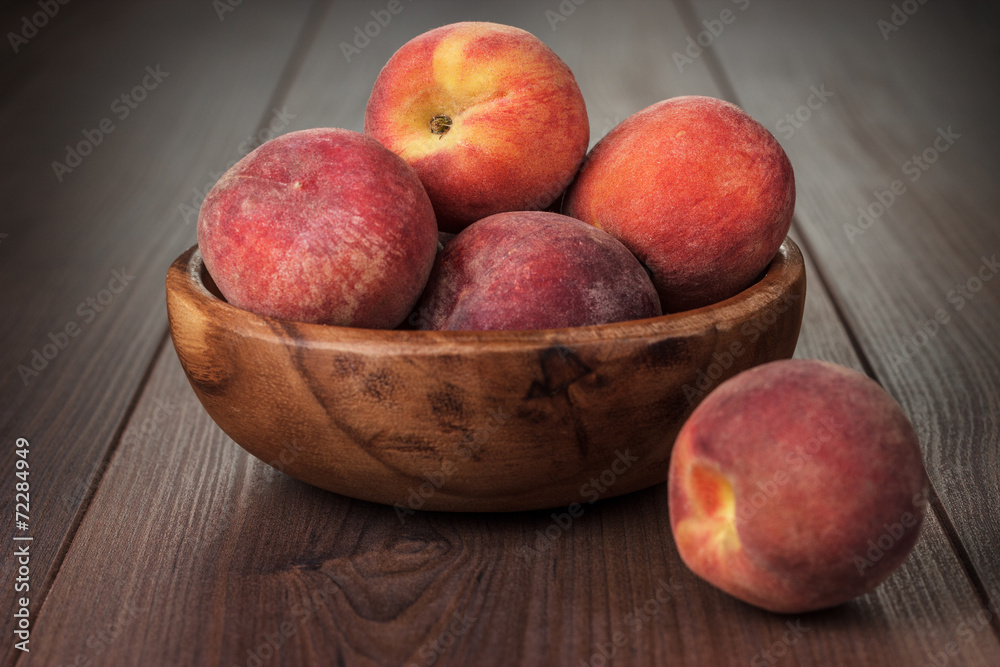 wooden bowl with some peaches on the table wooden bowl with some peaches on the table