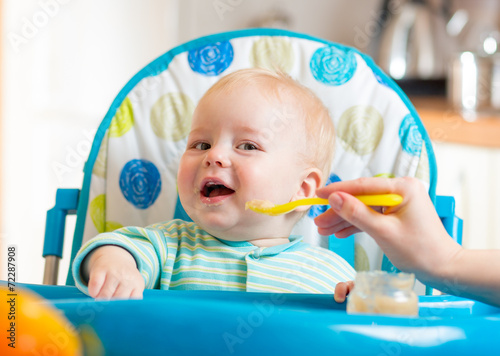 baby eating food on kitchen